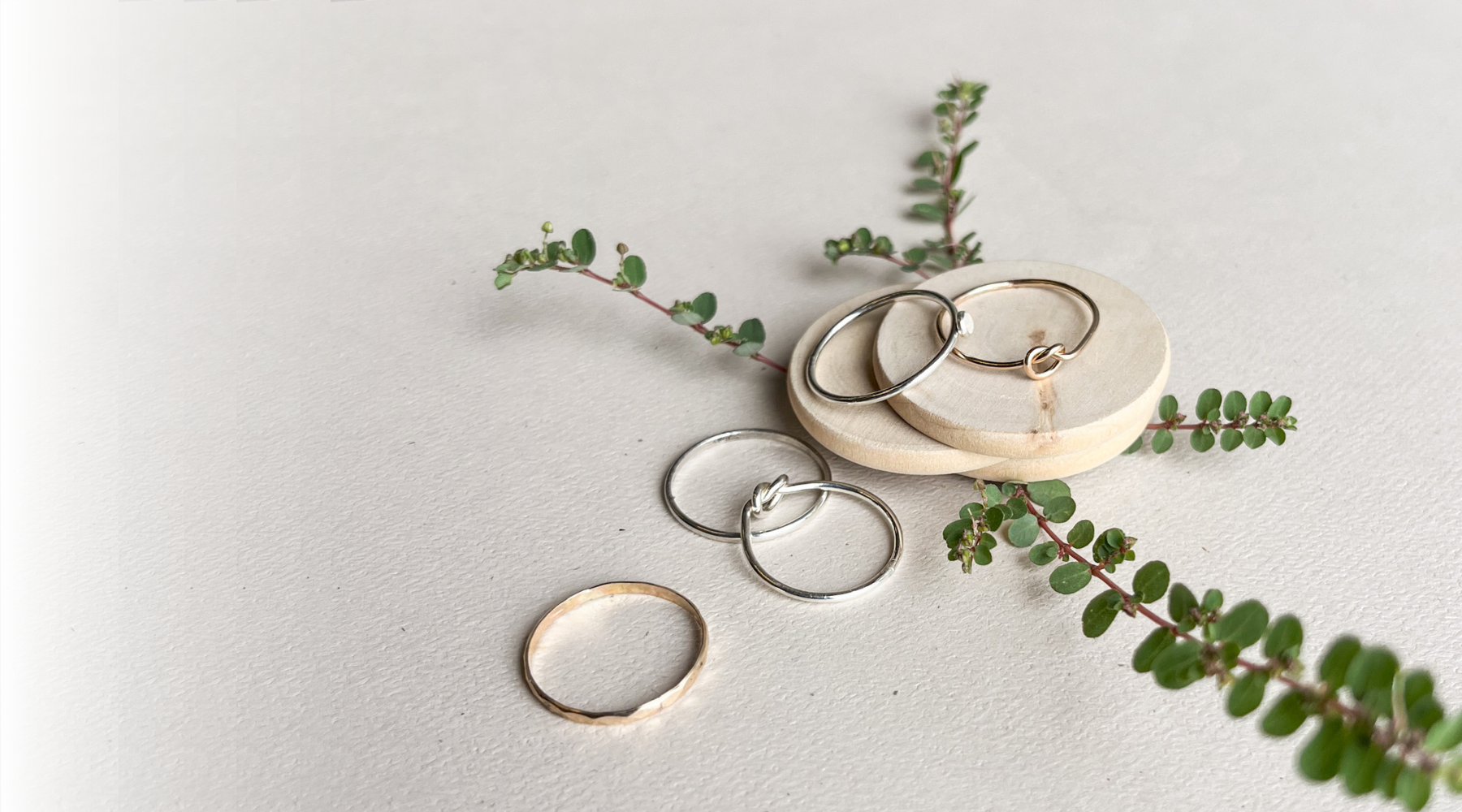 silver and gold stacking rings with wood and leaves in background