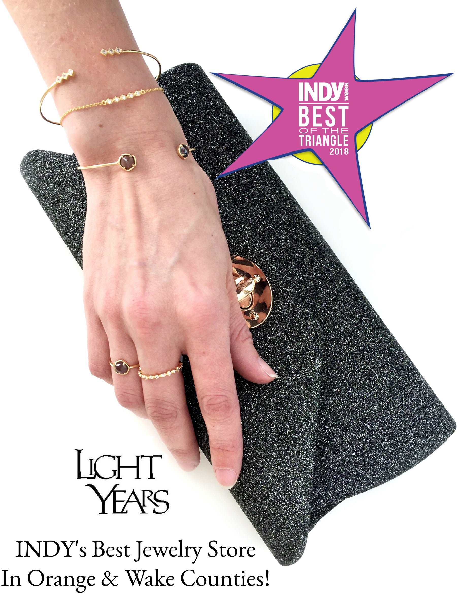 Image of a hand with jewelry holding a purse and a star that says Indy Best in the Triangle