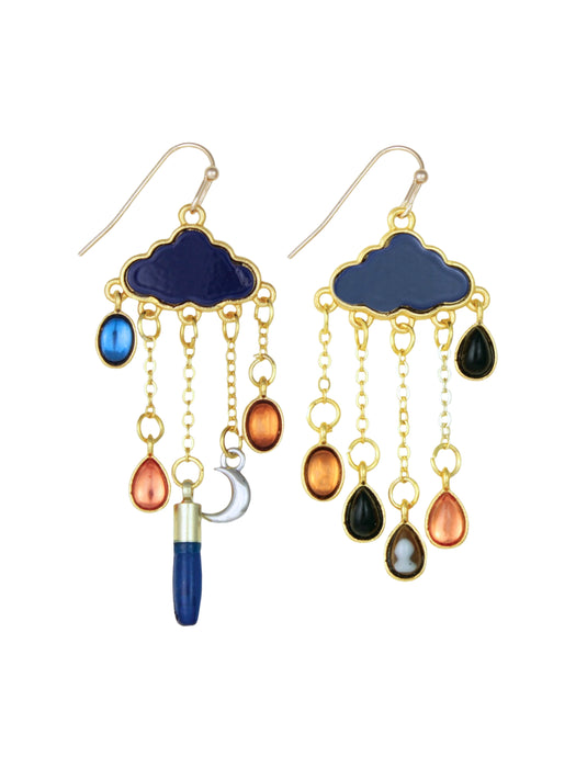 A pair of gold-tone cloud-shaped dangle earrings with dark blue enamel tops, hanging teardrop charms in blue, orange, black, and gray, and a small silver crescent moon charm, shown on a plain white background.