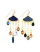 A pair of gold-tone cloud-shaped dangle earrings with dark blue enamel tops, hanging teardrop charms in blue, orange, black, and gray, and a small silver crescent moon charm, shown on a plain white background.